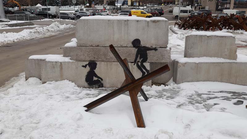 an image of an anti tank obstacle in front of street art in central kyiv