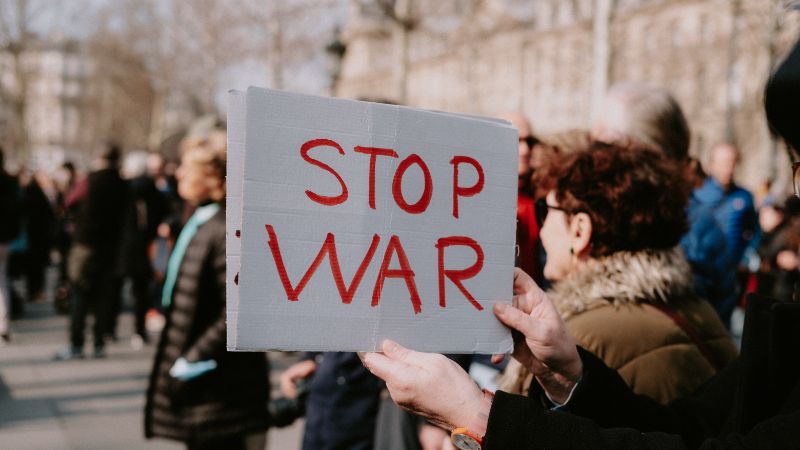 a woman at a march holding a sign that says stop war
