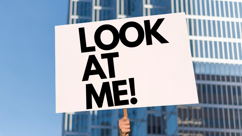 A person at a protest holding a sign that says "look at me"